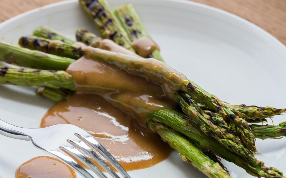 a bunch of hot griddled asparagus draped with a thick dark sesame sauce
