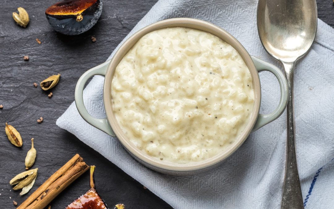 A bowl of creamy white rice pudding, served with a caramelised fig
