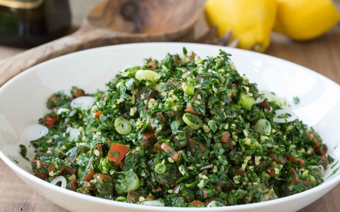 A bowl of bright green tabbouleh made with chopped parsley, spring onion, tomato and bulghar wheat