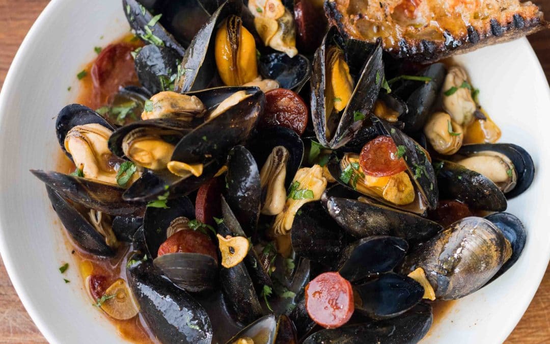 A bowl of steamed mussels with a sauce of chorizo, sherry, garlic and parsley