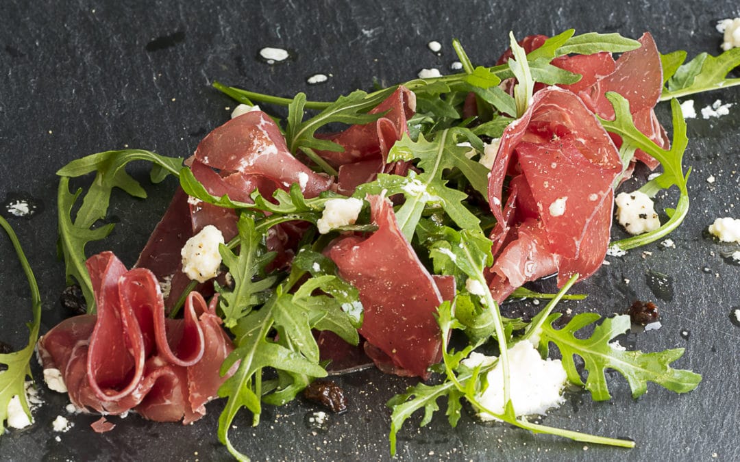 A salad of bresaola with wild rocket leaves, a dressing of crumbled goats cheese and sultanas steeped in balsamic vinegar