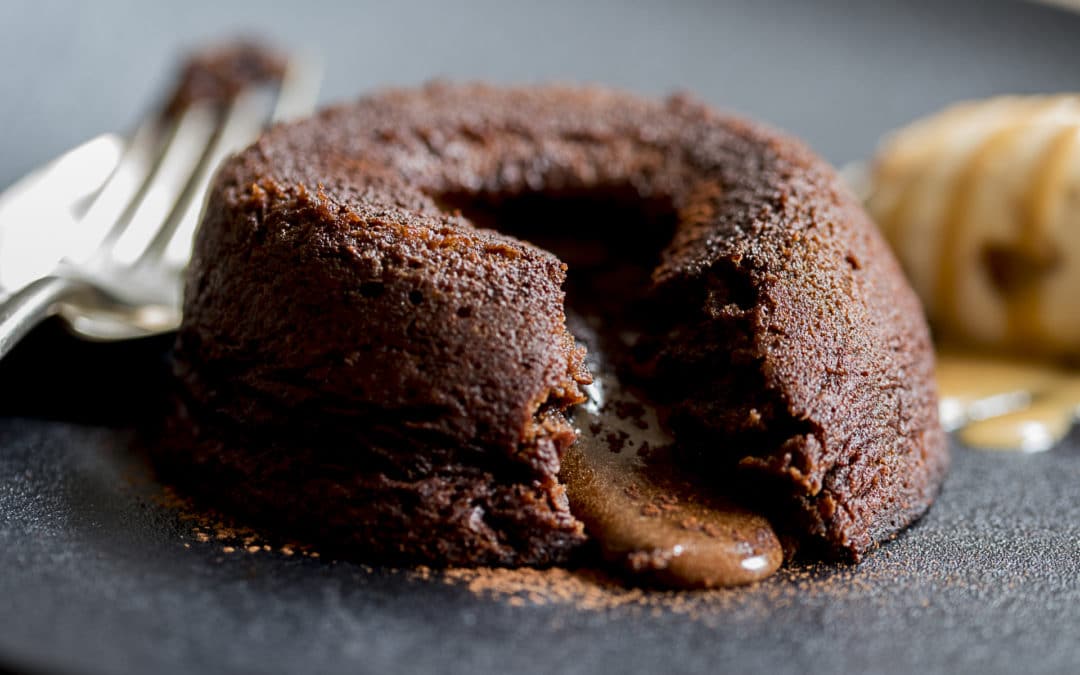 A chocolate fondant pudding oozing its liquid centre onto the plate