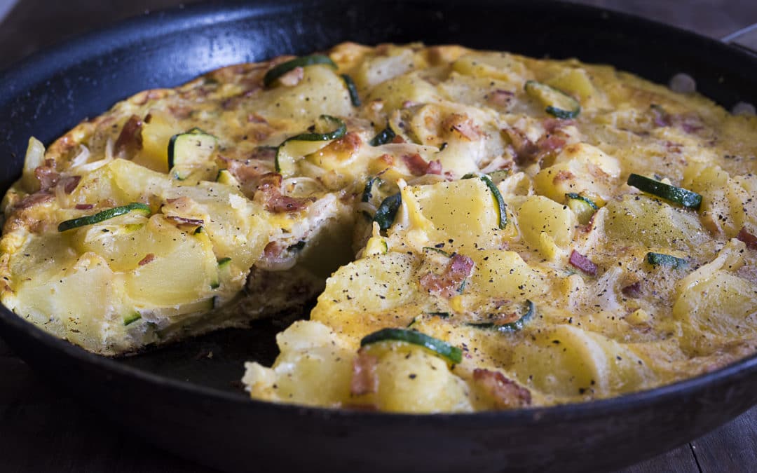 A otoat and courgette fritatta is set with eggs in a pan