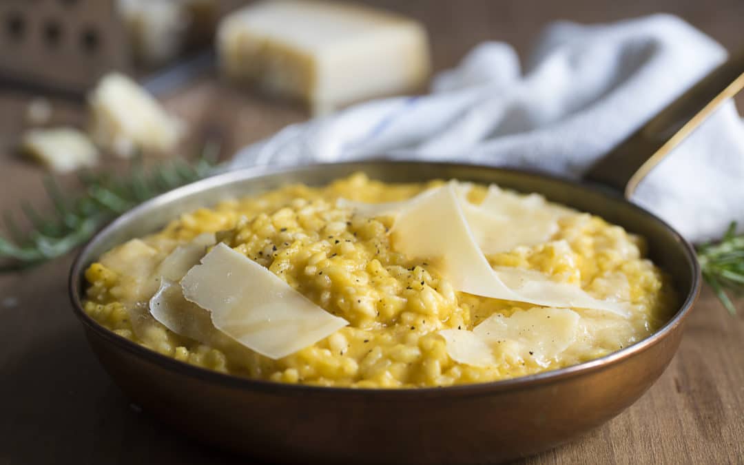 A pan of creamy orange butternut squash risotto topped with Parmesan shaving