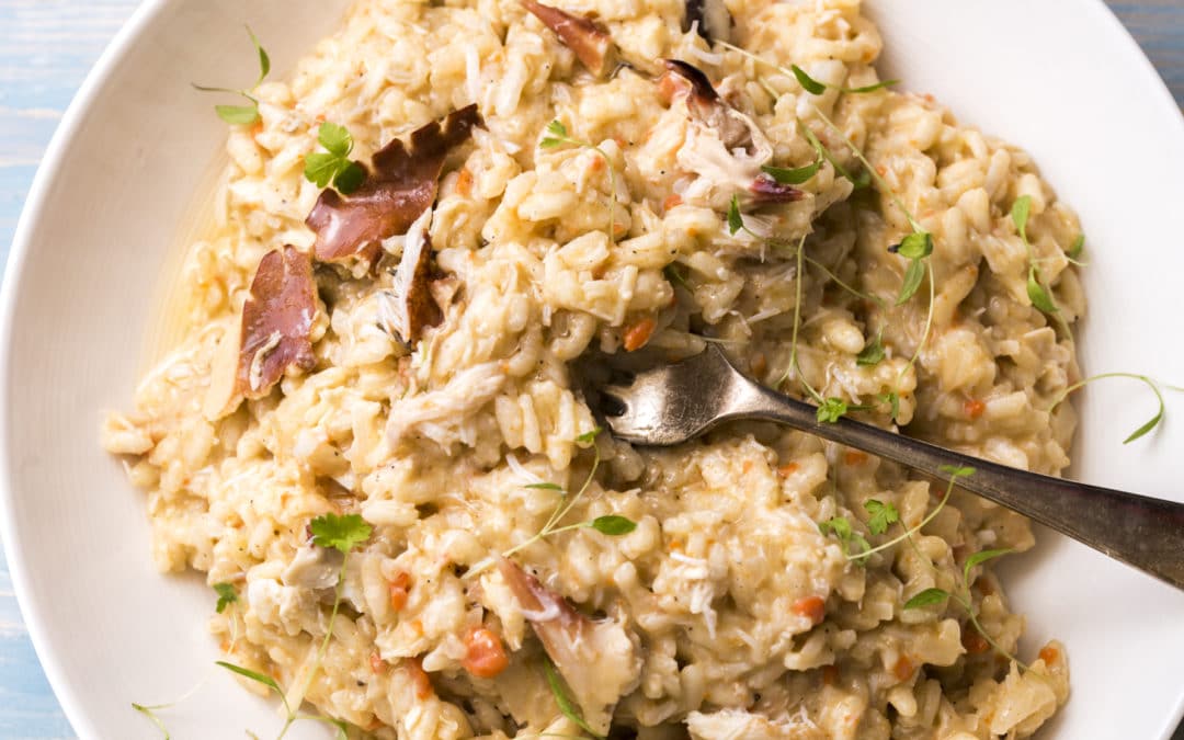 a bowl of crab risotto with chunks of fresh crab